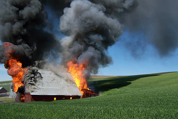 A wood and metal barn completely engulfed in flames