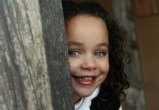 Little girl peeking around corner stock photo