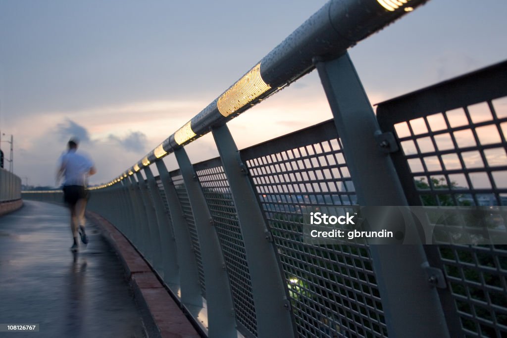 Homem pista de corrida ao longo da ponte ao pôr do sol - Foto de stock de Cidade royalty-free