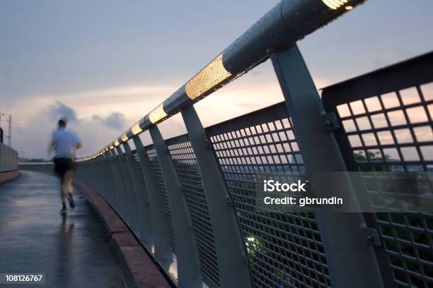 Foto de Homem Pista De Corrida Ao Longo Da Ponte Ao Pôr Do Sol e mais fotos de stock de Cidade