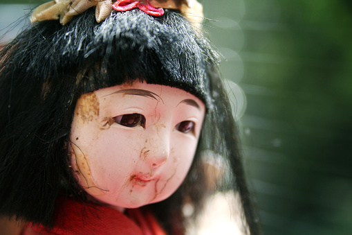 A close up shot of an antique doll's head showing the discolouration and cracks on her face.  But she has such a serene expression.