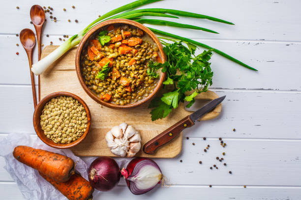 lentil soup in a wooden bowl and ingredients on a white wooden background, top view. - lentil imagens e fotografias de stock