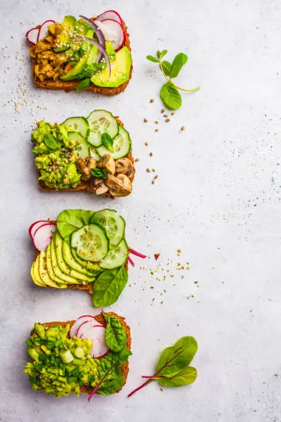 Photo of Avocado toasts with different toppings, top view, white background.