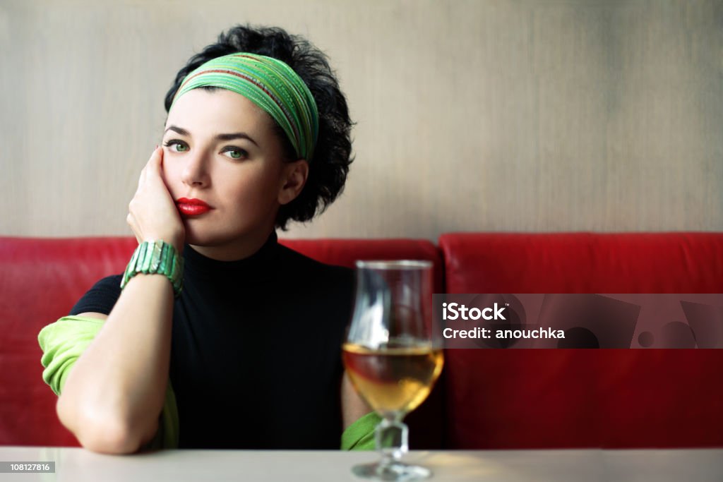 Portait de femme assise à une Table avec une boisson en verre - Photo de Bandana libre de droits