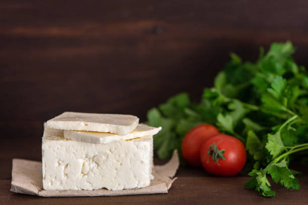 Large piece of feta cheese on dark wooden table. Selective focus Large piece of feta cheese on dark wooden table. Selective focus. feta cheese block stock pictures, royalty-free photos & images