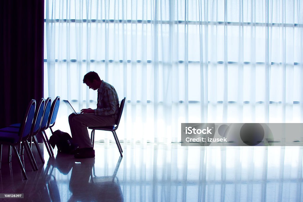 Hombre trabajando en portátil en el centro de convenciones de la habitación - Foto de stock de Adulto libre de derechos