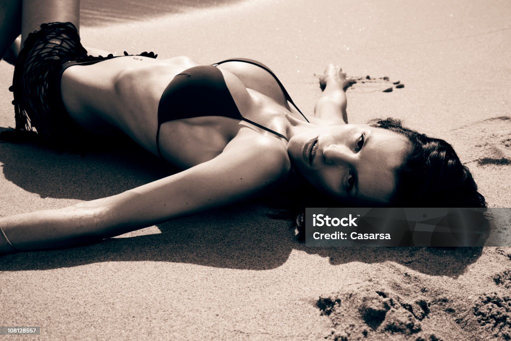 Giovane donna sdraiata sulla spiaggia, Viraggio seppia - Foto stock royalty-free di Adulto