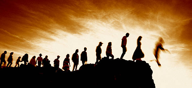 Line of People Walking Single File Off Cliff stock photo