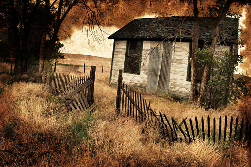 Composite photo of an abandoned house in a ghost town overlaid with dirty old paper.