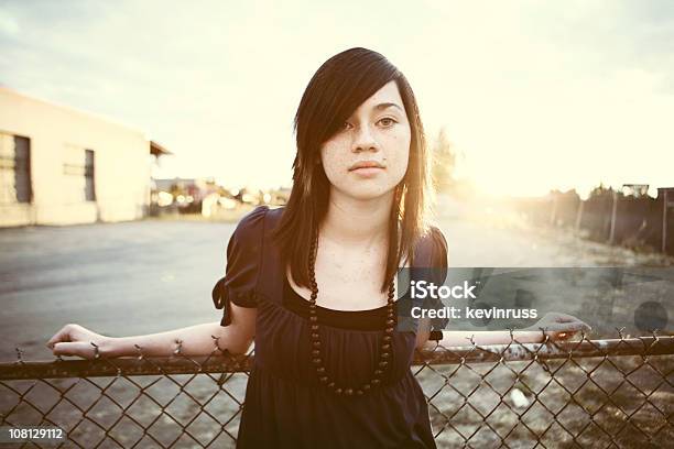 Young Woman Sitting Against Fence Stock Photo - Download Image Now - Adult, Adults Only, Beautiful People