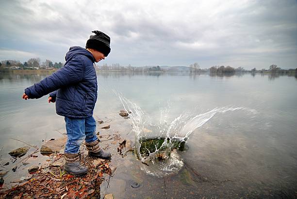 pequeno menino jogando big stone no lake - throwing stone little boys child - fotografias e filmes do acervo