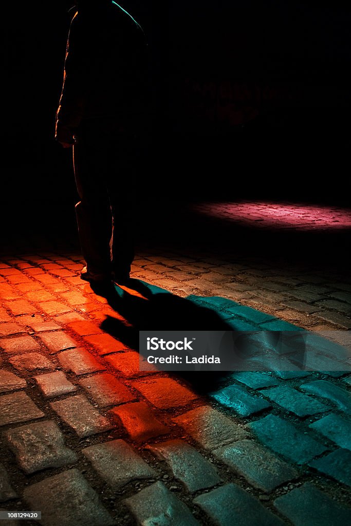 Hombre caminando por la calle de adoquines oscuro, bajo - Foto de stock de Noche libre de derechos