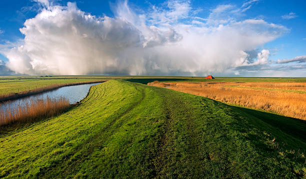 защитная дамба и облака - polder ст�оковые фото и изображения