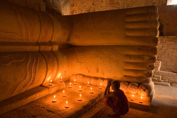 Young buddhist monk boy meditating while holding a religious text in a temple
