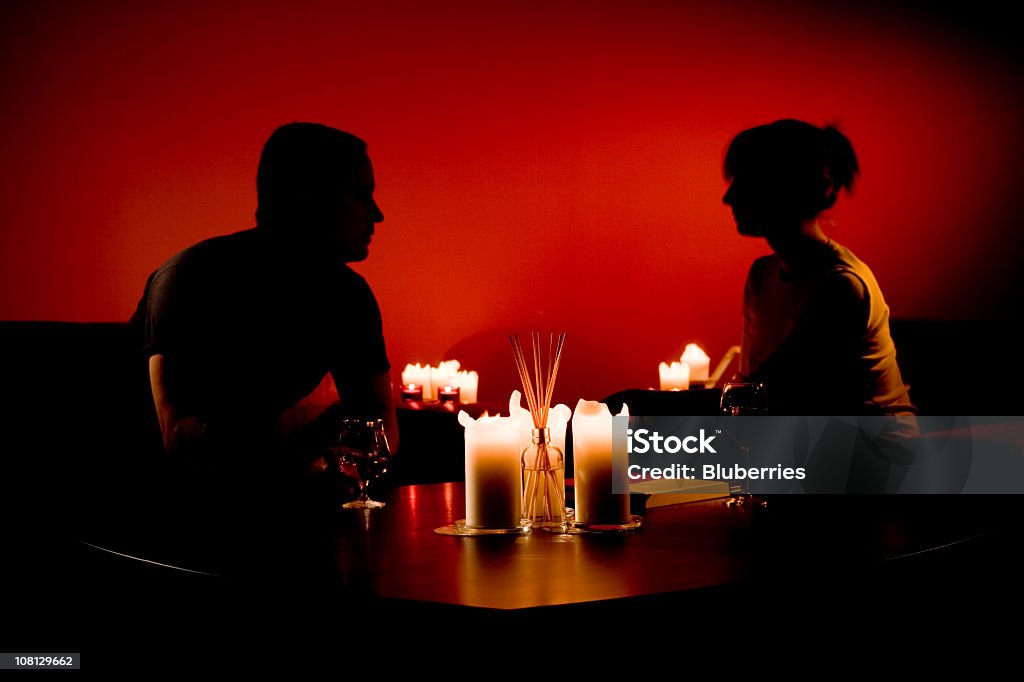 Silhouette des Mannes und der Frau sitzt mit verschiedenen Kerzen - Lizenzfrei Zweiertisch Stock-Foto