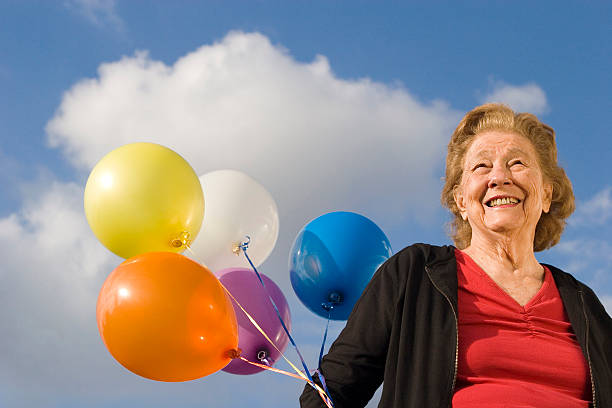 Senior woman holding balloons stock photo