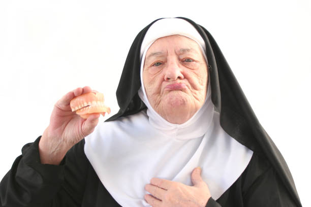 istock Senior Nun Holding Up Dentures, Isolated on White 108129829
