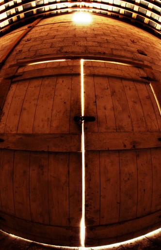 Antique wooden barrel with metal stays.  Hanging from the barrel are parts and pieces of various farm equipment, traps, and tools.