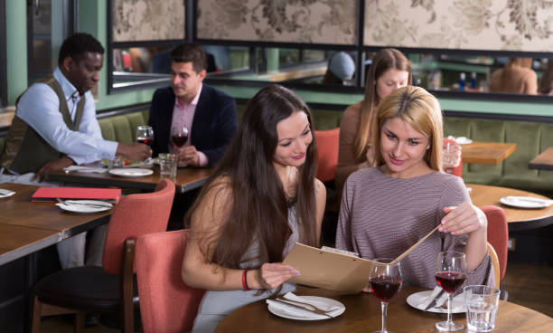 istock Two female friends with menu card in restaurant 1081328868