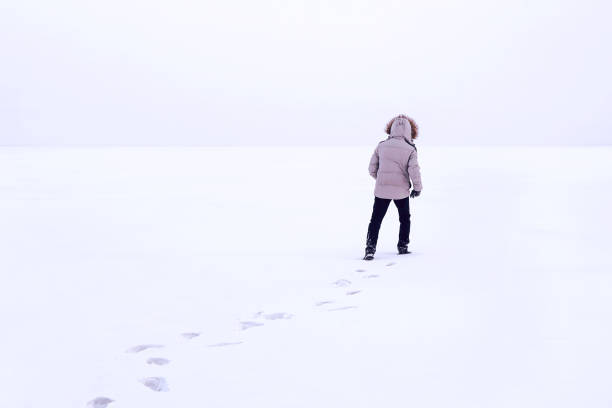 istock Man walking on snow, footprints in snow, behind 1081328922