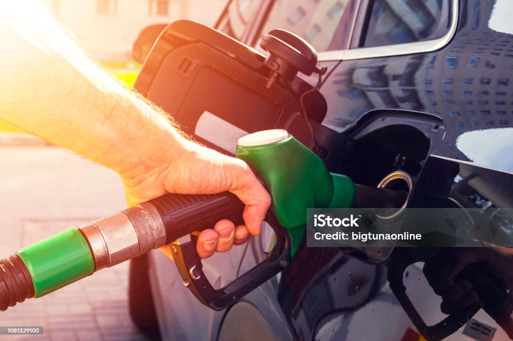 Refuelling the car at a gas station fuel pump. Man driver hand refilling and pumping gasoline oil the car with fuel at he refuel station. Car refuelling on petrol station. Fuel pump at station Gasoline Stock Photo