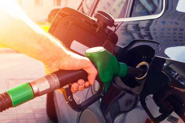 Refuelling the car at a gas station fuel pump. Man driver hand refilling and pumping gasoline oil the car with fuel at he refuel station. Car refuelling on petrol station. Fuel pump at station stock photo