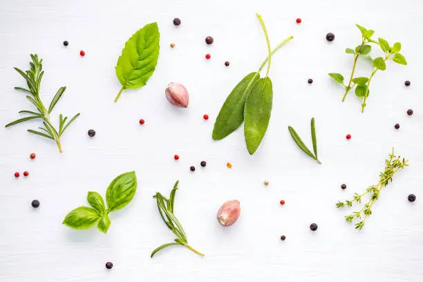 Photo of Various of spices and herbs on wooden background. Flat lay spices ingredients rosemary, thyme, oregano, sage leaves and sweet basil on white wooden.