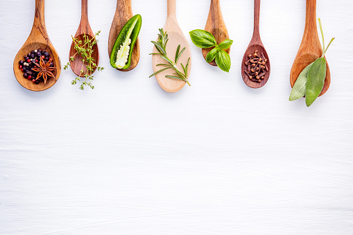 Various of spices and herbs on wooden background. Flat lay spices ingredients rosemary, thyme, oregano, sage leaves and sweet basil on white wooden.