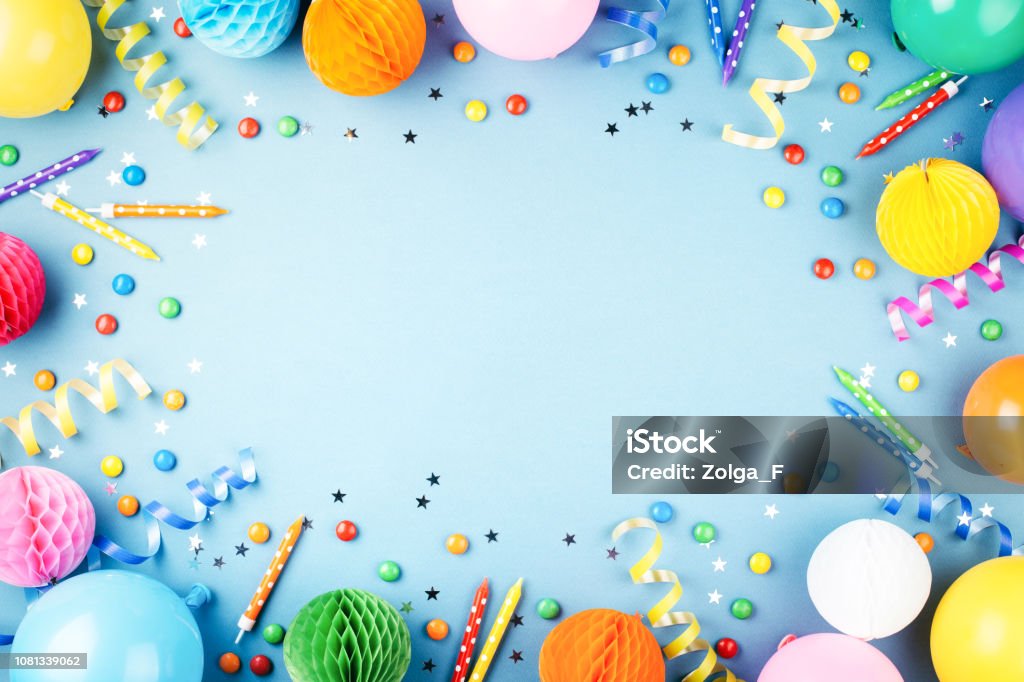 Birthday party background. Birthday party background on blue. Top view. Frame made of colorful serpentine, balloons, candles, candies and confetti. Birthday Stock Photo