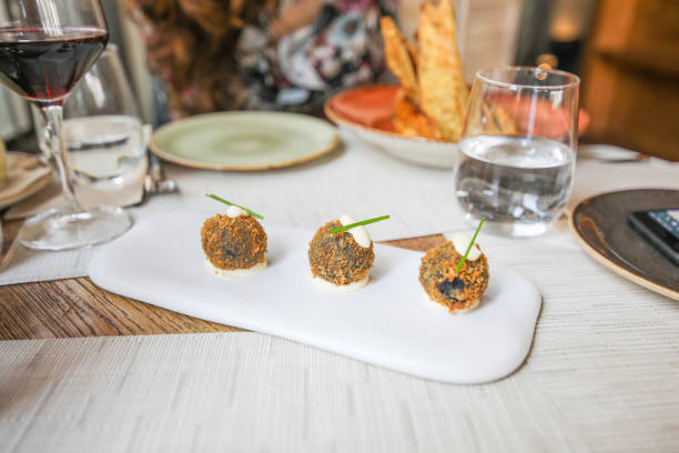 December 30th,2023,San Sebastian,Basque Spain: Locals and Tourists are ordering and enjoying eating Pinchos at a Pinchos Bar. Pincho is also known as Pintxo or Tapas, which is originally born in San Sebastián and became the most popular snack for spanish people before dinner. Pinchos pub crawl is one of the most popular activities for tourists also for locals.