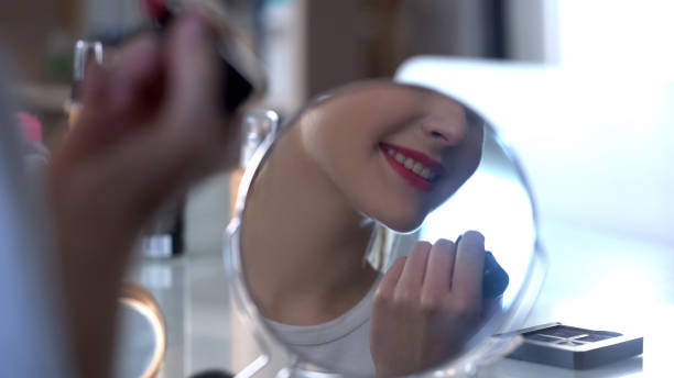 istock Lady putting seductive evening makeup smiling to her reflection in mirror 1081346462