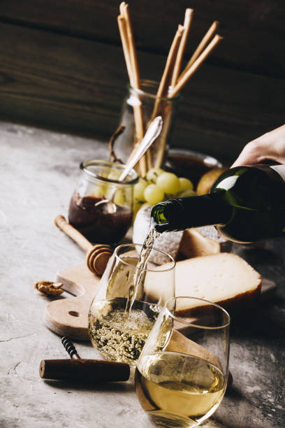 white wine pouring into glasses with charcuterie assortment on the stone background - 3500 imagens e fotografias de stock