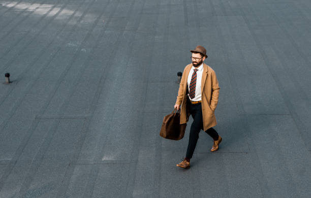 istock handsome bearded businessman with hat and bag walking on roof 1081349566
