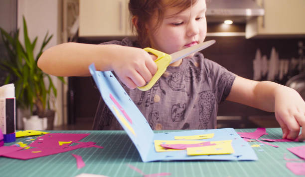 istock Little girl cutting colored paper with scissors 1081350286