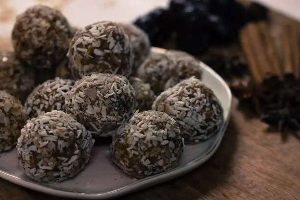 Healthy raw vegan sweet balls with  coconut, dates, almond on a wooden board background. Vegan candy, cinnamon, anis, ginger, almond flakes. Copy space
