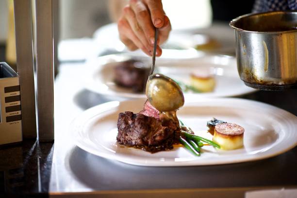 steak auf einem teller, in der ein koch küche sauce gegossen wird vorbereitet - steak filet mignon gourmet fillet stock-fotos und bilder
