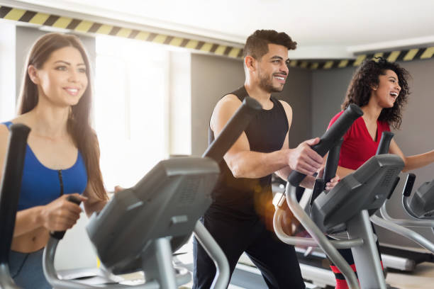 jeunes gens exerçant sur le cross-trainer dans la salle de gym - cross trainer photos et images de collection