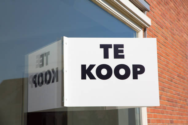 Sales board on house with text Te Koop or For Sale stock photo