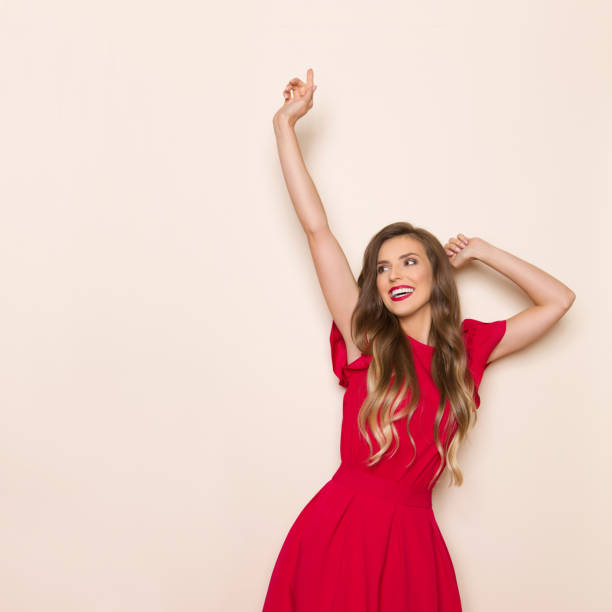 Happy Young Woman In Red Dress Is Looking Away And Gesturing stock photo