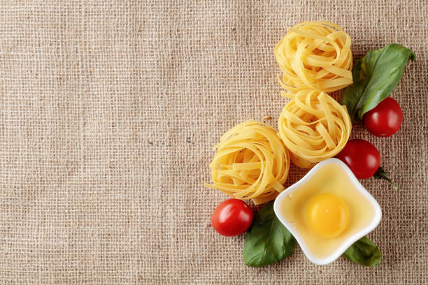 Homemade raw egg noodles with tomato and basil. Top view, copy space.