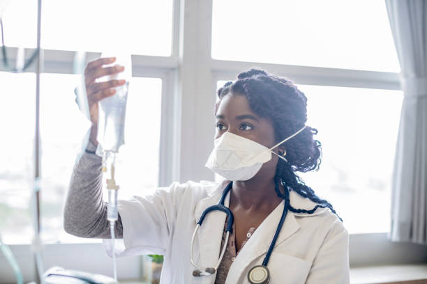 istock Young woman wearing face mask checking IV drip 1081389920