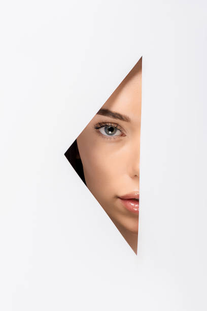 istock partial view of attractive girl looking at camera through hole on white 1081396384