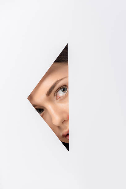 istock beautiful young woman looking away through hole on white 1081396418