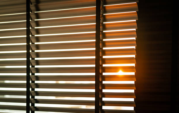 istock Opened venetian plastic blinds with sunlight in the morning. White plastic window with blinds. Interior design of living room with window horizontal blinds. Window slatted shades made of plastic. 1081399164