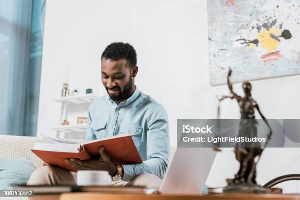 Selective Focus Of African American Man Reading Book In Living Room Stock Photo - Download Image Now