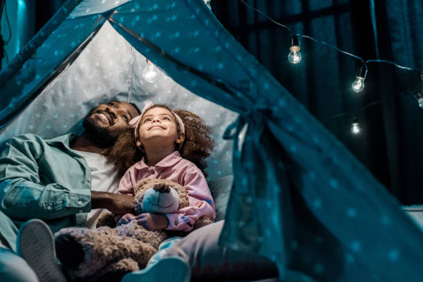 americano africano padre mirando hacia arriba con la hija de wigwam en sala de estar - teepee fotografías e imágenes de stock