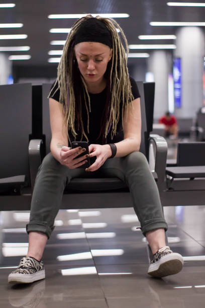 istock young woman with dreadlocks using smartphone at the airport at night. having fun 1081424302