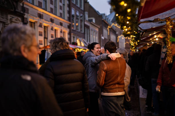 Young woman reaches out to hug and embrace a young man at a Christmas street market stock photo