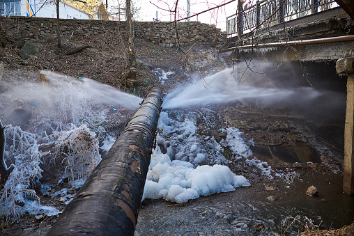 Water pressure from a large pipe over the river, in winter