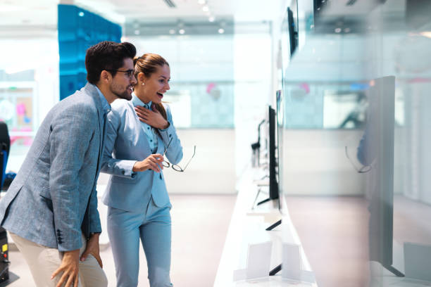 istock Beautiful multicultural couple dressed elegant standing and looking for new tv. Tech store interior. 1081438384